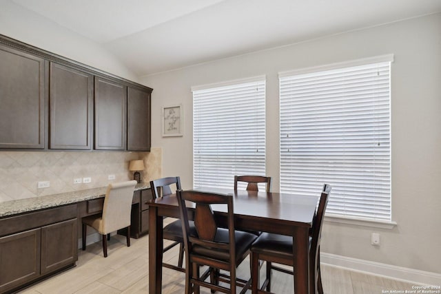 dining room with vaulted ceiling, built in desk, and baseboards