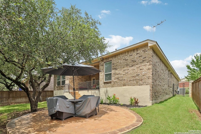 rear view of house with brick siding, a patio, central air condition unit, a lawn, and a fenced backyard