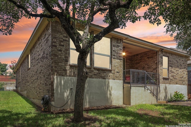 view of property exterior with a yard, brick siding, and a porch