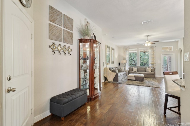 interior space with arched walkways, dark wood-style flooring, visible vents, and baseboards