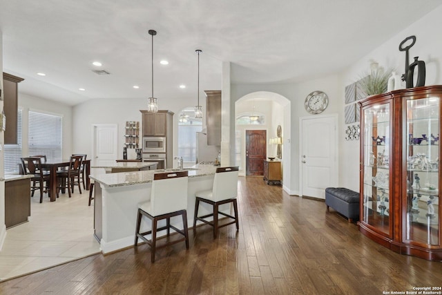 kitchen with arched walkways, appliances with stainless steel finishes, hardwood / wood-style flooring, and visible vents