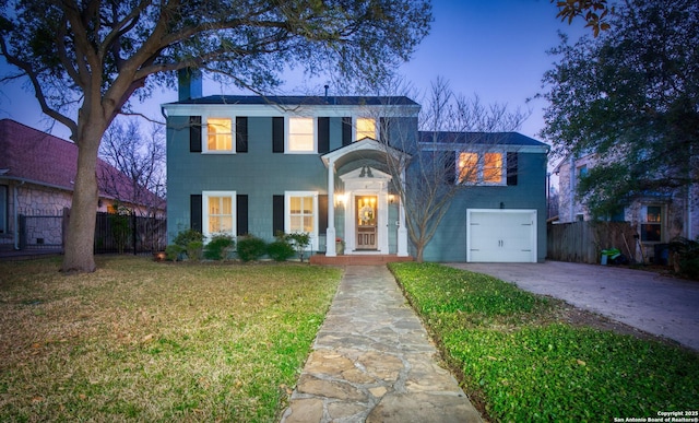 traditional-style house with a garage, a chimney, fence, and concrete driveway