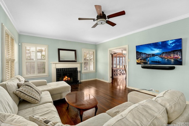 living room with ceiling fan, wood finished floors, baseboards, ornamental molding, and a tiled fireplace