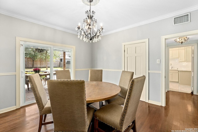 dining space with a chandelier, ornamental molding, wood finished floors, and visible vents