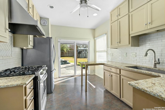 kitchen featuring stainless steel gas range oven, a ceiling fan, light stone counters, extractor fan, and a sink