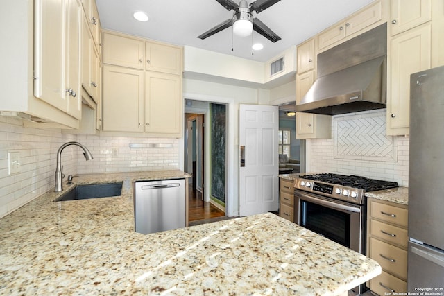 kitchen featuring stainless steel appliances, visible vents, cream cabinets, a sink, and exhaust hood