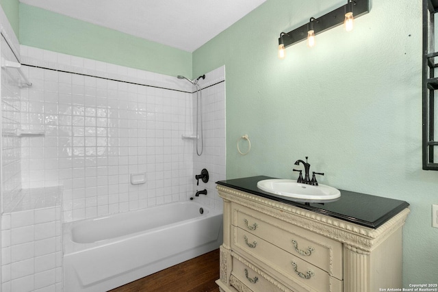 bathroom with washtub / shower combination, vanity, and wood finished floors