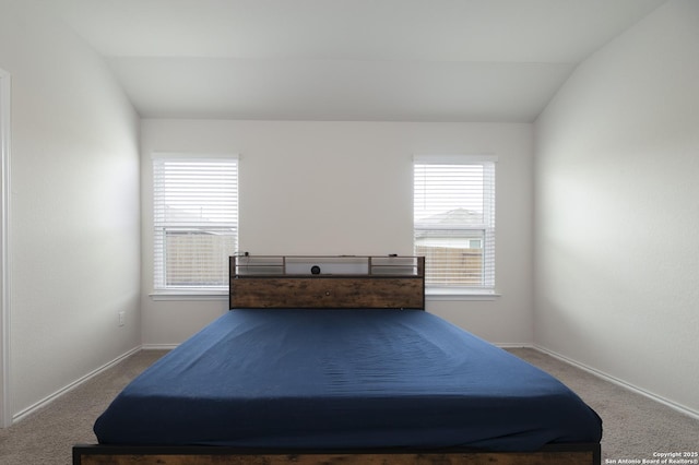 carpeted bedroom with vaulted ceiling and baseboards