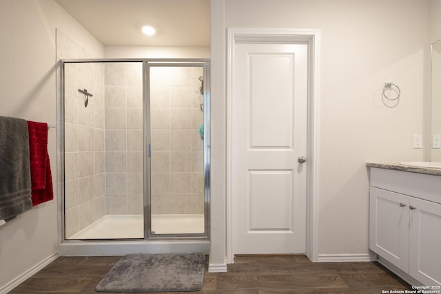 full bathroom with a stall shower, baseboards, wood finished floors, and vanity