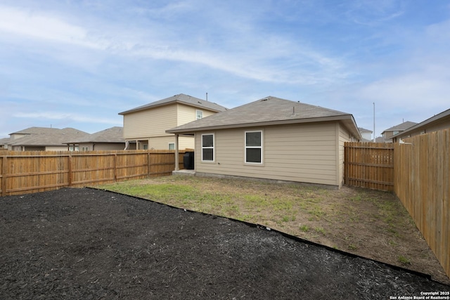 rear view of house featuring a yard and a fenced backyard