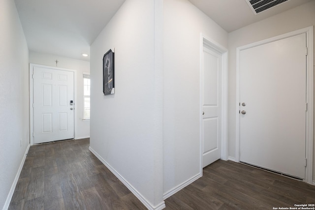 hallway with dark wood-type flooring, visible vents, and baseboards