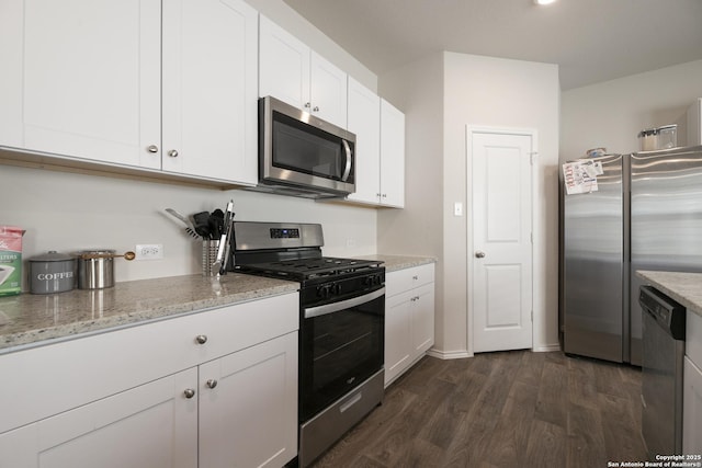 kitchen with appliances with stainless steel finishes, dark wood finished floors, light stone counters, and white cabinets