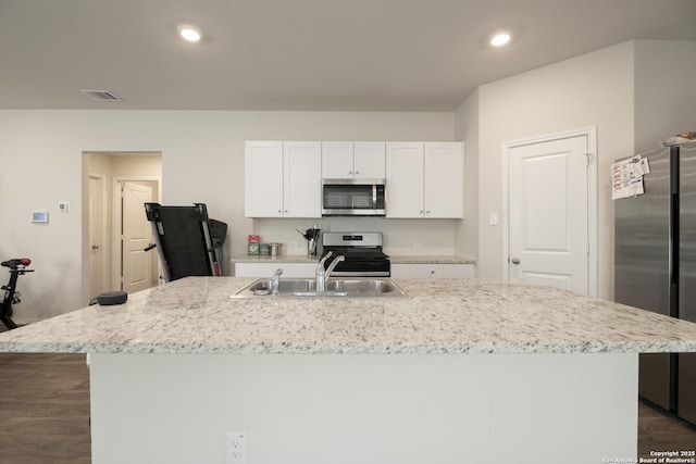 kitchen featuring visible vents, white cabinets, an island with sink, stainless steel appliances, and a sink