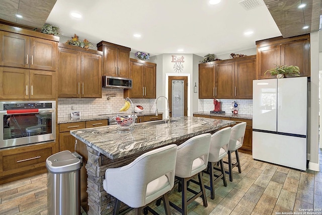 kitchen featuring appliances with stainless steel finishes, wood finish floors, visible vents, and a kitchen bar