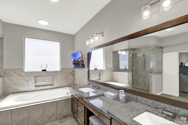 bathroom featuring a bath, a shower stall, double vanity, and a sink