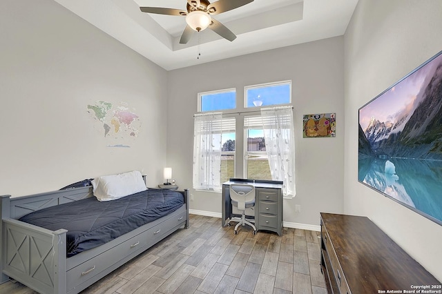 bedroom featuring ceiling fan, wood finished floors, a raised ceiling, and baseboards