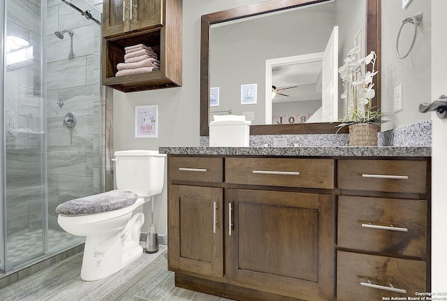 bathroom with toilet, a shower stall, ceiling fan, and vanity