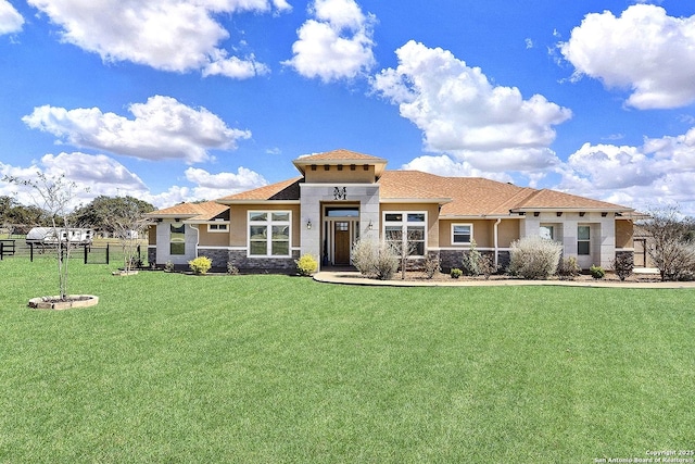 view of front of property featuring a front yard, stone siding, fence, and stucco siding