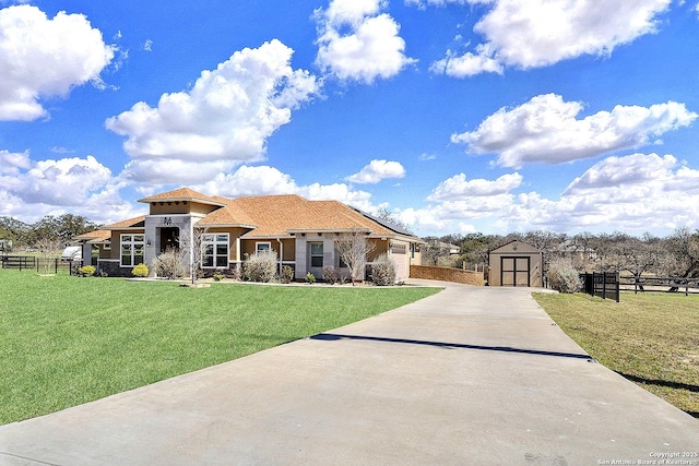 view of front of house with a storage shed, driveway, a front lawn, and fence