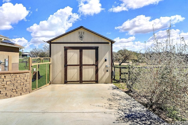 view of shed featuring driveway, a gate, and fence