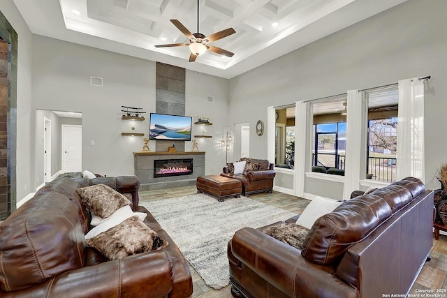 living area with a fireplace, visible vents, a towering ceiling, coffered ceiling, and baseboards