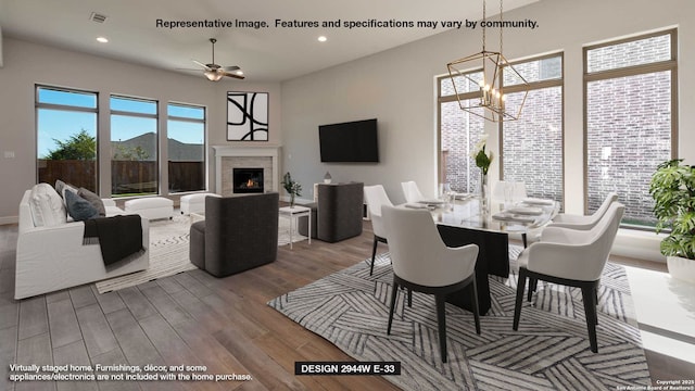 dining space featuring recessed lighting, ceiling fan with notable chandelier, wood finished floors, visible vents, and a glass covered fireplace