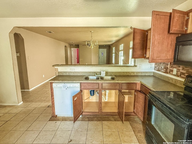 kitchen with light tile patterned floors, a chandelier, a peninsula, brown cabinets, and black appliances