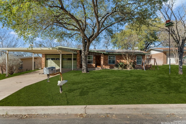 single story home with a garage, solar panels, concrete driveway, a front lawn, and brick siding