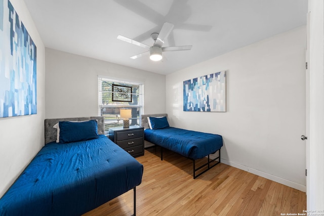 bedroom with ceiling fan, light wood-style flooring, and baseboards