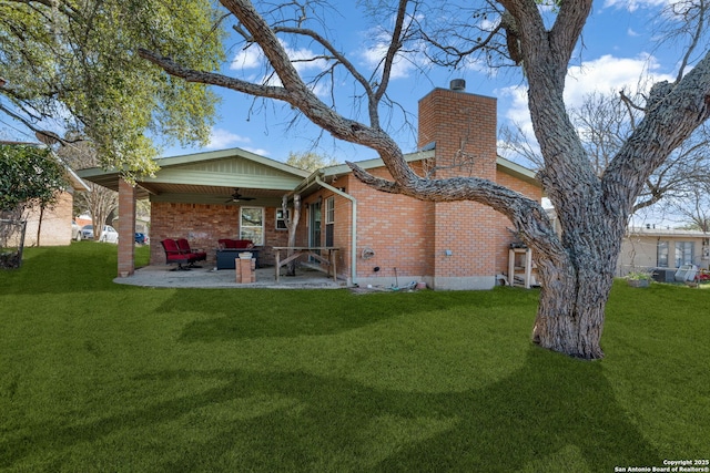 back of property featuring brick siding, a lawn, a patio area, and a ceiling fan