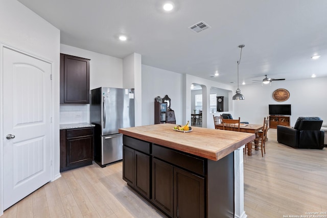 kitchen with arched walkways, visible vents, wooden counters, freestanding refrigerator, and open floor plan