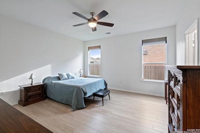 bedroom with light wood-style flooring, visible vents, ceiling fan, and baseboards