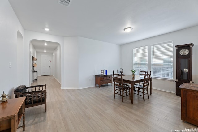 dining room featuring arched walkways, visible vents, light wood-style flooring, and baseboards