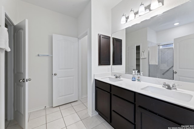 bathroom featuring double vanity, tiled shower, tile patterned flooring, and a sink