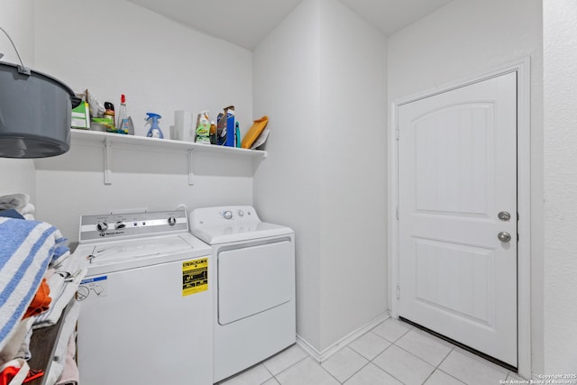 clothes washing area with light tile patterned floors, laundry area, independent washer and dryer, and baseboards