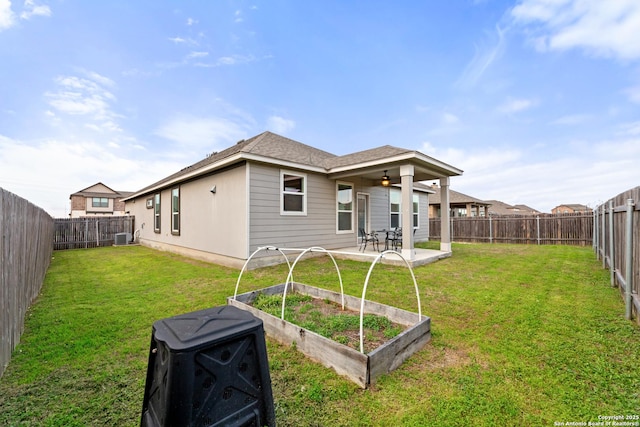 rear view of house featuring a patio, a fenced backyard, a garden, a ceiling fan, and a lawn