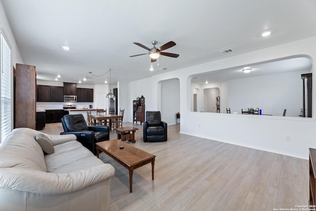 living area featuring arched walkways, ceiling fan, recessed lighting, visible vents, and light wood finished floors