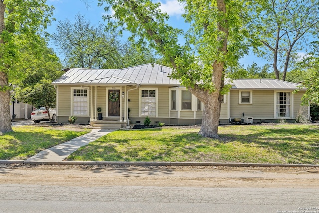 view of front facade featuring a standing seam roof, a front yard, metal roof, and crawl space