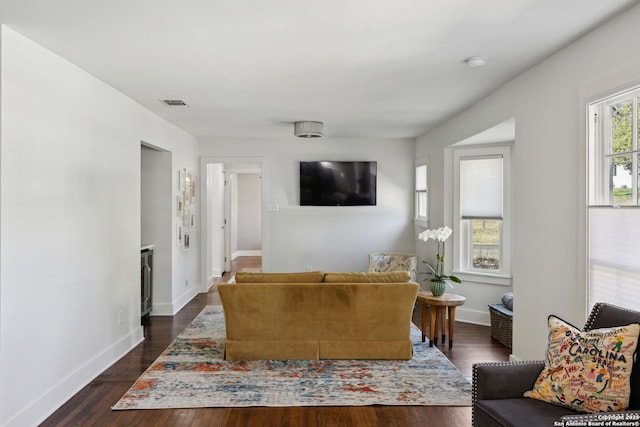 living area with dark wood-style flooring, visible vents, and baseboards