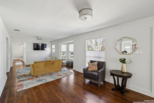 living room featuring dark wood-type flooring, baseboards, and visible vents