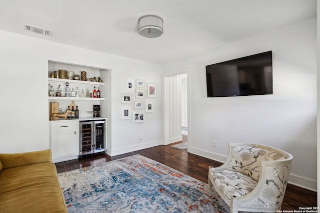 living room featuring dark wood finished floors, a dry bar, visible vents, wine cooler, and baseboards