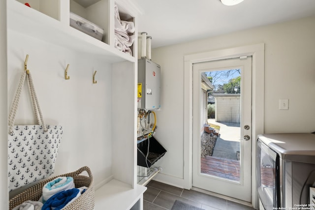 mudroom featuring dark tile patterned flooring, tankless water heater, and washer and clothes dryer