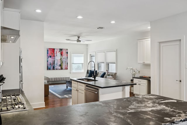 kitchen with ceiling fan, an island with sink, visible vents, dark wood-style flooring, and a sink