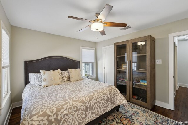 bedroom featuring dark wood-type flooring, visible vents, baseboards, and multiple windows