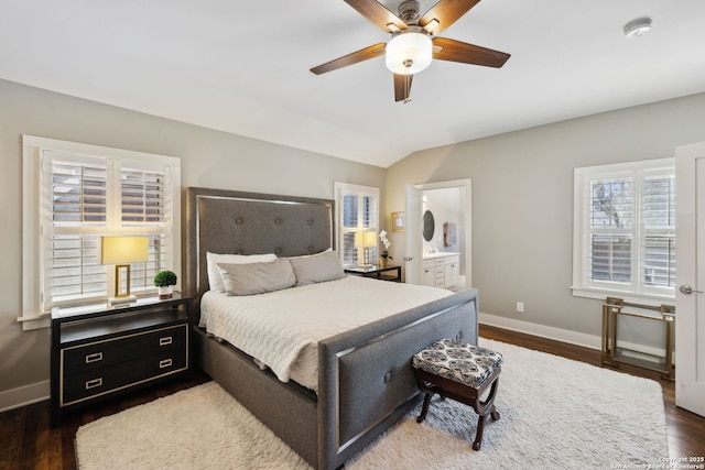 bedroom featuring baseboards, vaulted ceiling, ensuite bath, a ceiling fan, and wood finished floors