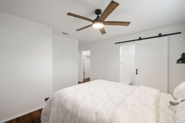 bedroom with a barn door, baseboards, visible vents, a ceiling fan, and dark wood-style flooring