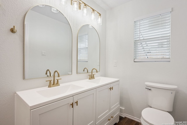 bathroom with double vanity, wood finished floors, a sink, and toilet