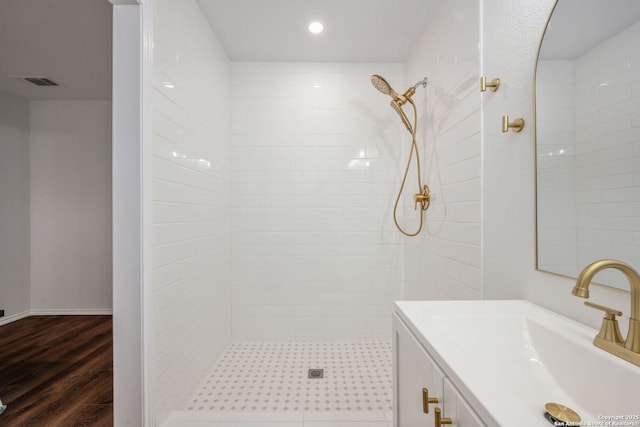 full bath featuring recessed lighting, visible vents, vanity, wood finished floors, and tiled shower