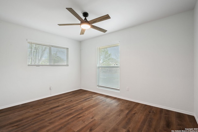 empty room featuring dark wood finished floors, a ceiling fan, and baseboards