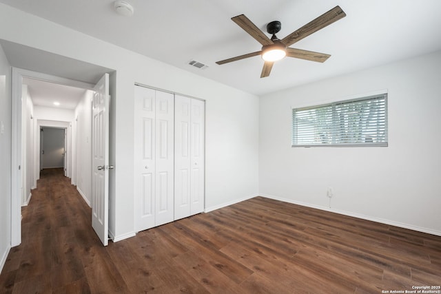 unfurnished bedroom featuring ceiling fan, wood finished floors, visible vents, baseboards, and a closet